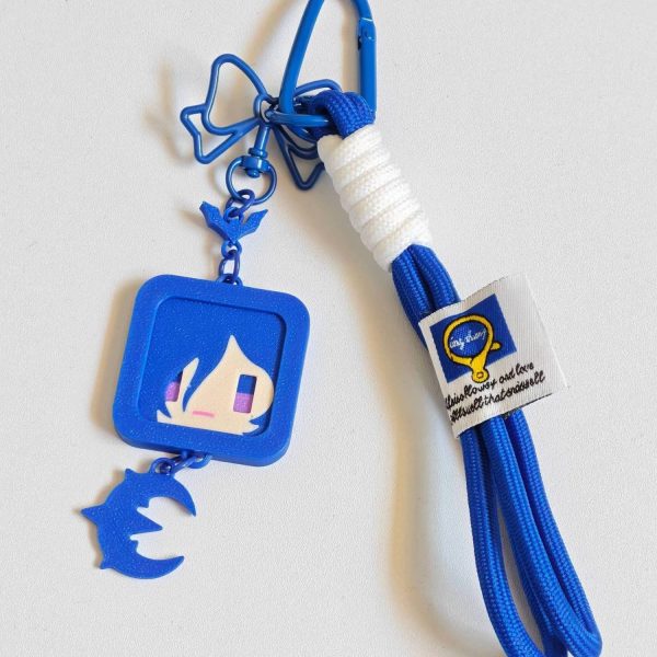 A high-quality blue ZZZ Promeia keychain featuring a square character frame, crescent moon charm, and a braided paracord strap with a bow-shaped clasp.