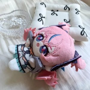 A 10cm sitting chibi plush keychain of Nicole Demara from Zenless Zone Zero, featuring pink hair with a blue streak, large embroidered eyes, and a blue halo accessory on the back.