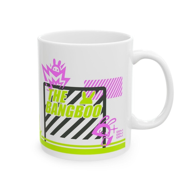 Two white ceramic mugs sitting on a wooden desk next to a laptop, featuring neon green and pink retro cyberpunk graphics of Bangboo from Zenless Zone Zero.