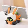 Cute Zenless Zone Zero Eous Bangboo soft silicone figure holding a smartphone horizontally on a white desk.